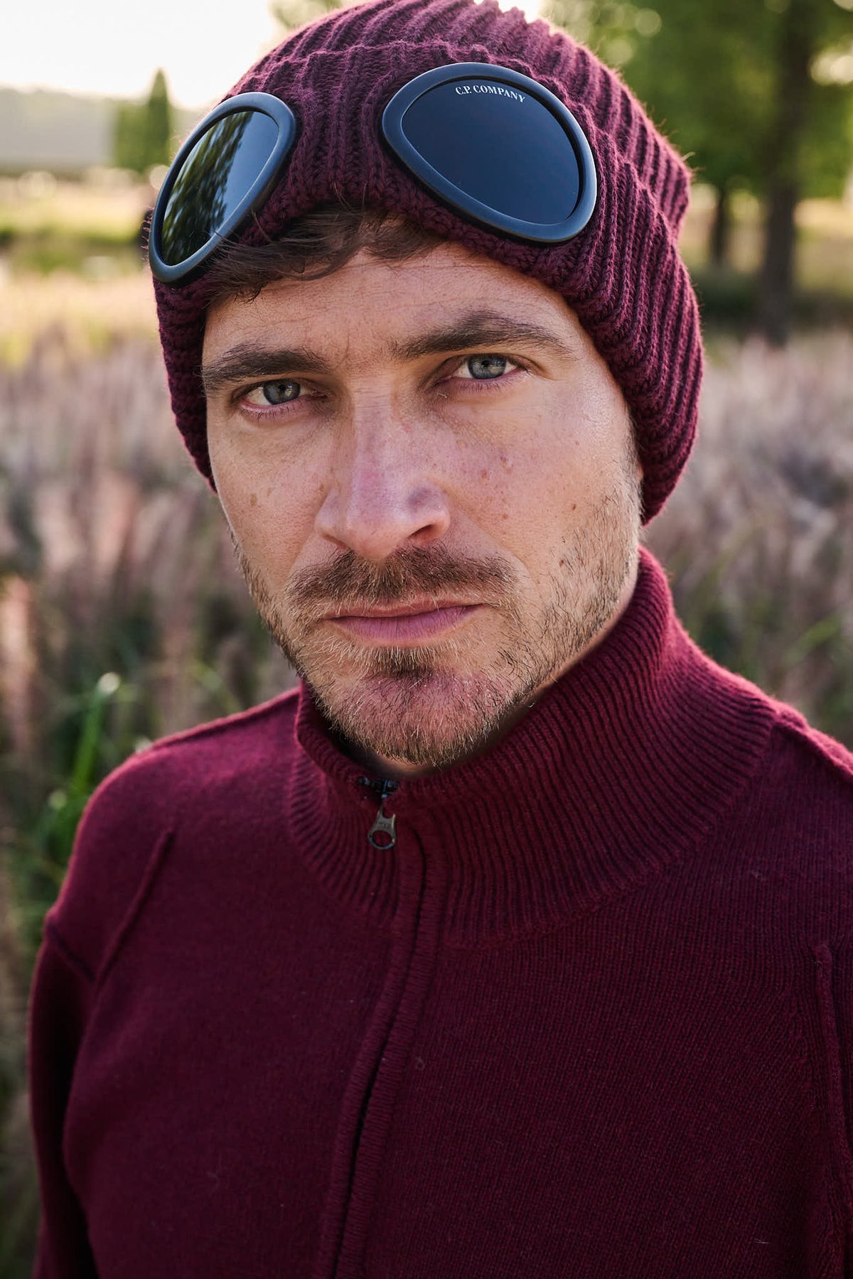 Burgundy C.P. Company herenlook met iconische lens uit The Hidden Estate FW26