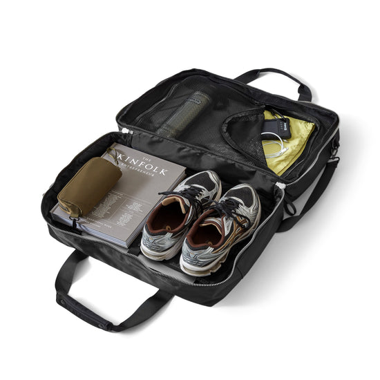 AY Studios Weekend Bag Black reistas, opengelegd met schoenen, kleding en accessoires