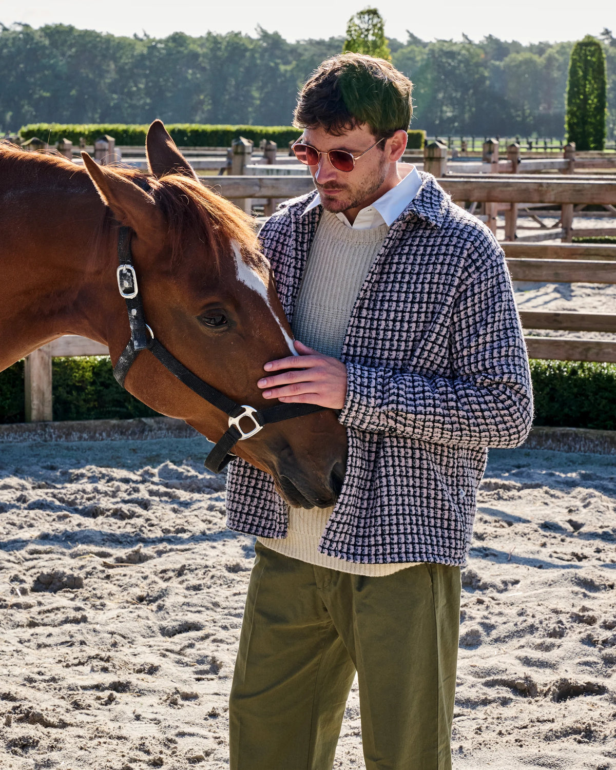 Bouclé ruitovershirt met ecru knitwear en groene plooibroek naast een paard aan de paddock van Begijnhoeve.