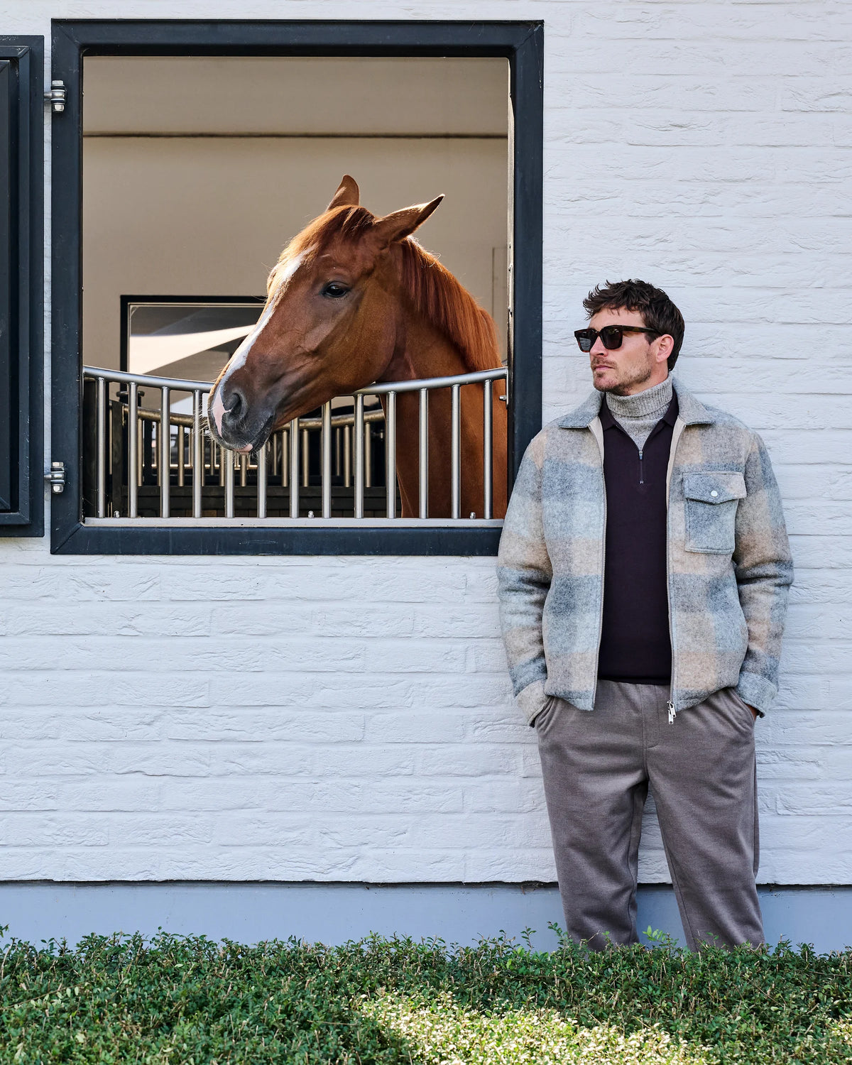 Licht geruit Genti overshirt met bordeaux onderlaag en taupe broek bij een stalraam op Begijnhoeve.