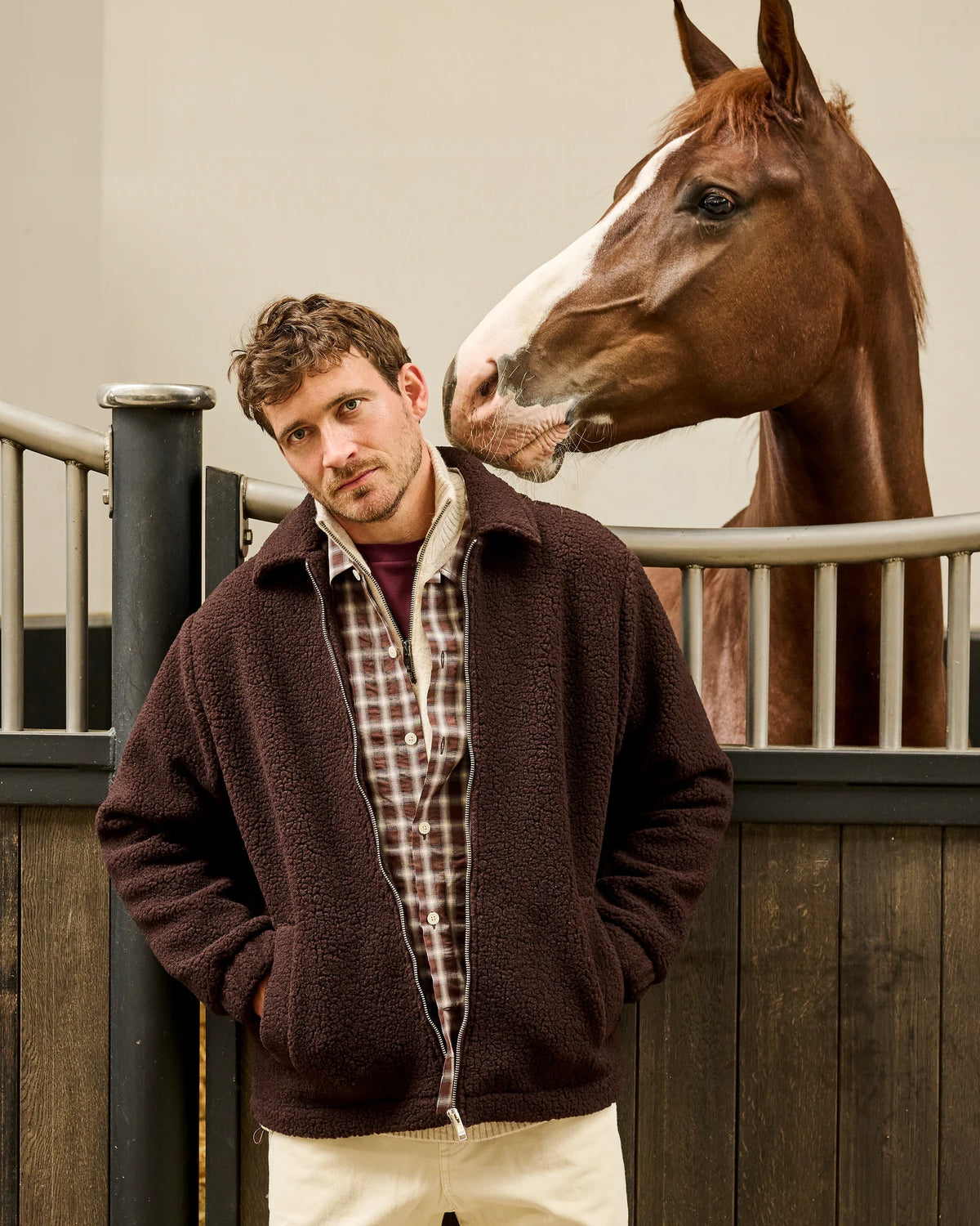 Chocoladebruine teddyjas van The GoodPeople met geruit hemd naast een paard in de stallen van Begijnhoeve.