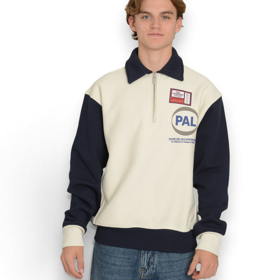 PAL Sporting Goods Pre Game Half Zip in Marshmallow, gedragen vooraanzicht met donkerblauwe mouwen, kraag en PAL-borstlogo.