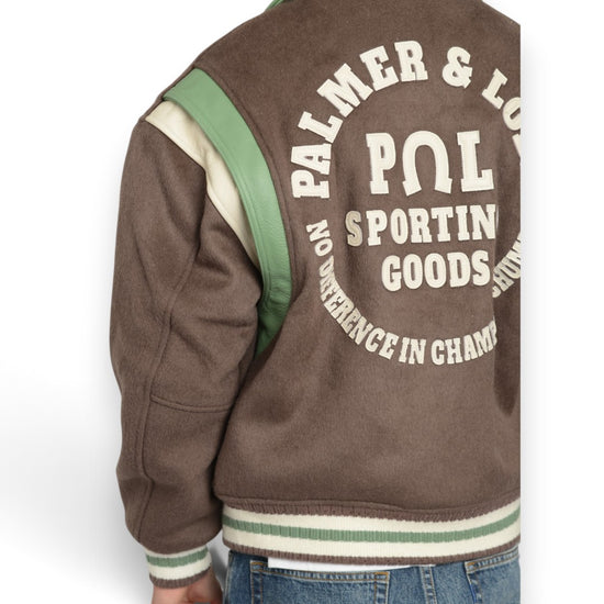 Detail van de PAL-rugborduring, groene schouderpanelen en gestreepte boord op de Ranch Varsity Jacket in Deep Mahogany.