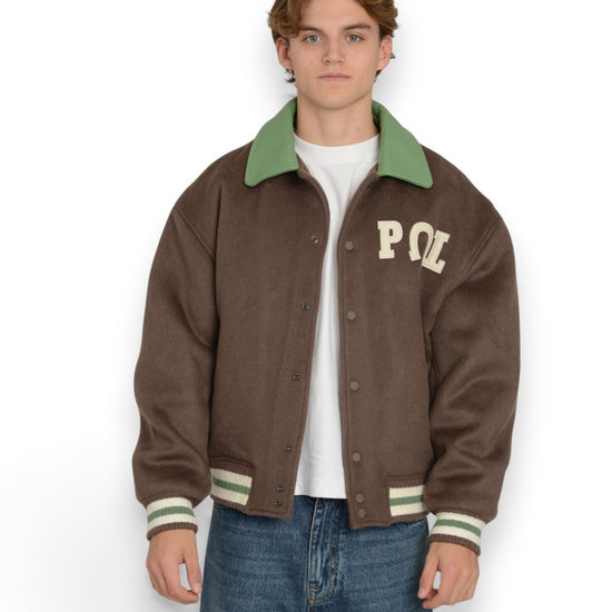 PAL Sporting Goods Ranch Varsity Jacket in Deep Mahogany, gedragen vooraanzicht met borstlogo, groene kraag en contrasterende boorden.