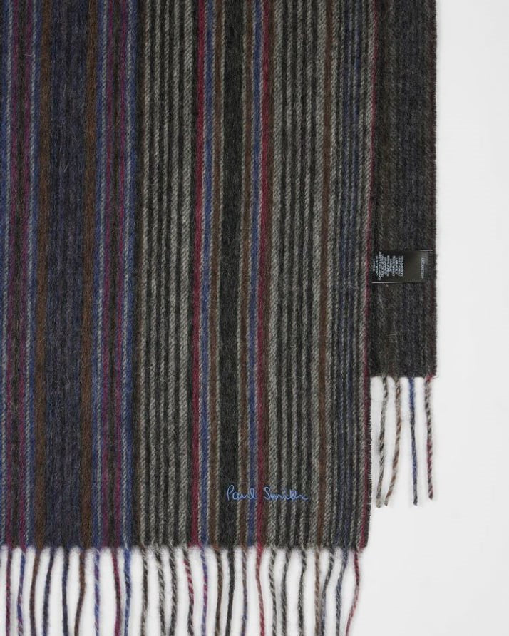 Detail van de franjes en het geborduurde Paul Smith-logo op de grijze lamswollen sjaal