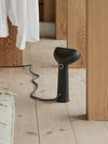 Steamery Cirrus 3 Iron Steamer donkergrijze kledingstomer op een houten vloer naast kleding