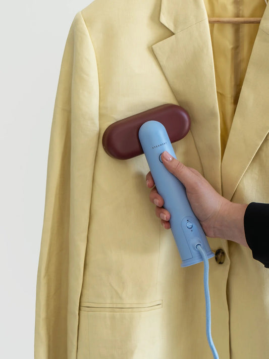 Steamery Cirrus Lite Travel Steamer blauwe reisstomer in gebruik op een lichtgeel vest