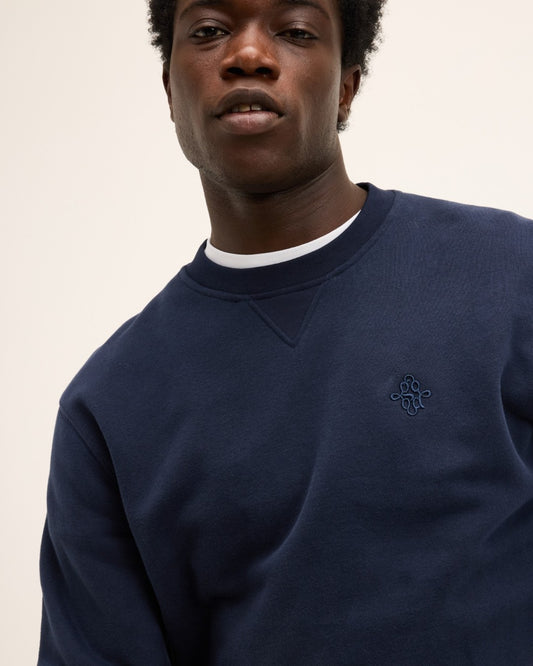The GoodPeople Lommy donkerblauwe sweater, detail van hals en borstlogo