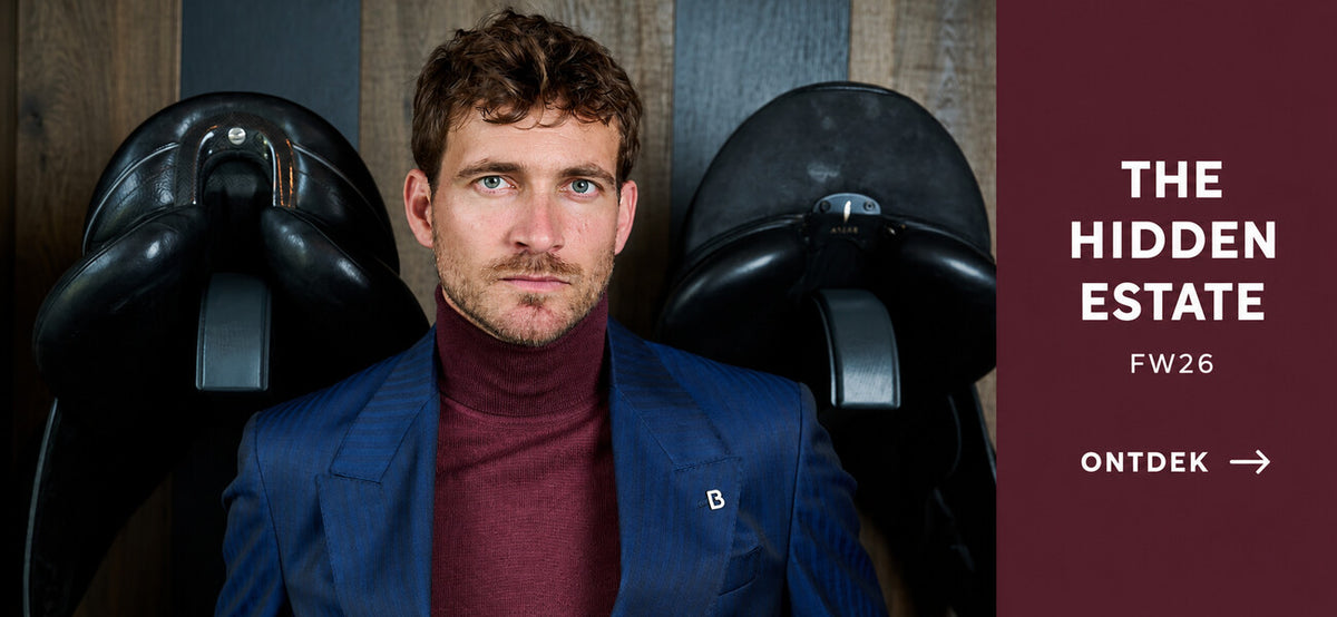 The Hidden Estate FW26 bij Checkpoint Mol: blauw pak met bordeaux coltrui in de zadelkamer van Begijnhoeve in Mol-Postel. Ontdek de nieuwe looks.