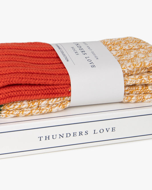 Thunders Love Cocktail Orange sokken, detail van de oranje ribboord en papieren band op de verpakking