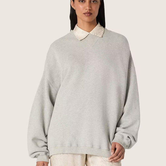 Vrouwelijk model met Golden Goose unisex sweatshirt in grijs melange en geborduurd Golden logo op de rug