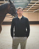 Donkere zip knit met lichte geruite broek naast een paard in de rijpiste op Begijnhoeve in Mol-Postel.