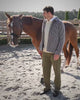 Bouclé ruitovershirt met lichte knitwear en groene broek naast een paard aan de paddock op Begijnhoeve in Mol-Postel.