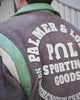 Bruin varsity jacket met groene kraag en ruime groene broek in de paardenstal op Begijnhoeve in Mol-Postel.