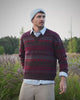 Trui met bordeaux en grijs patroon, lichtblauw hemd, beige broek en blauwe muts tussen het groen op Begijnhoeve in Mol-Postel.
