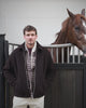 Donkerbruine teddy jas met geruit hemd en lichte broek naast een paard op Begijnhoeve in Mol-Postel.